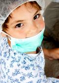 Kleines Mädchen mit Mundschutz spielt Arzt