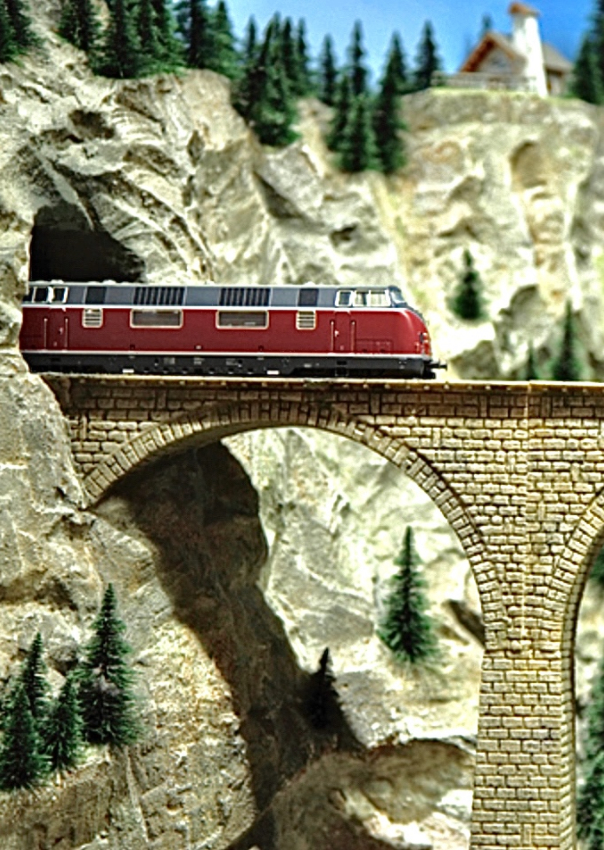 Modellzig fährt aus dem Tunnel auf eine Brücke 