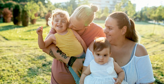 Familie mit zwei kleinen Kindern auf einer Wiese mit Hochhaus im Hintergrund