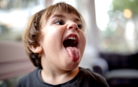 Wilder kleiner Junge streckt die Zunge raus